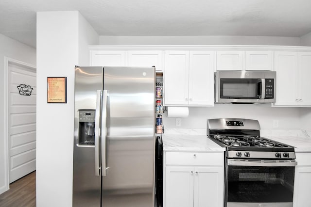 kitchen with dark hardwood / wood-style floors, light stone countertops, white cabinetry, and stainless steel appliances