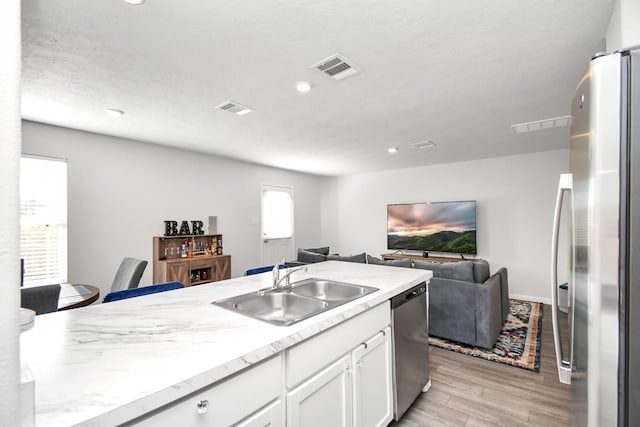 kitchen with light hardwood / wood-style floors, sink, white cabinetry, and stainless steel appliances