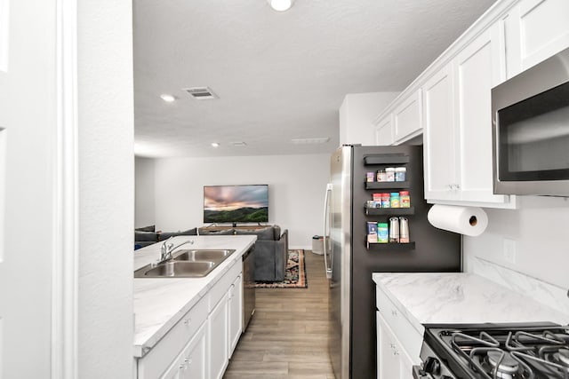 kitchen featuring hardwood / wood-style floors, white cabinetry, sink, and stainless steel appliances