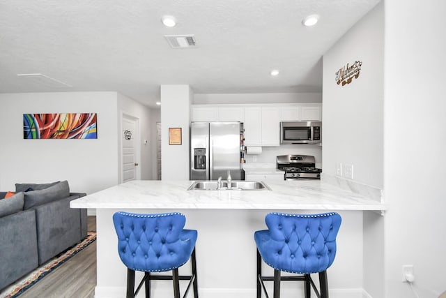 kitchen with white cabinets, a kitchen breakfast bar, sink, kitchen peninsula, and stainless steel appliances