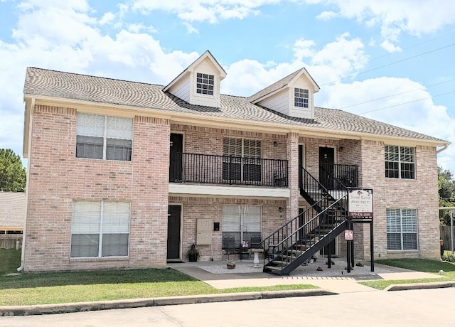 view of front facade featuring a front yard and a balcony