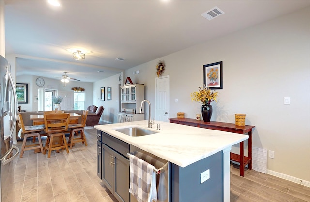 kitchen featuring ceiling fan, light hardwood / wood-style floors, a kitchen island with sink, sink, and stainless steel appliances