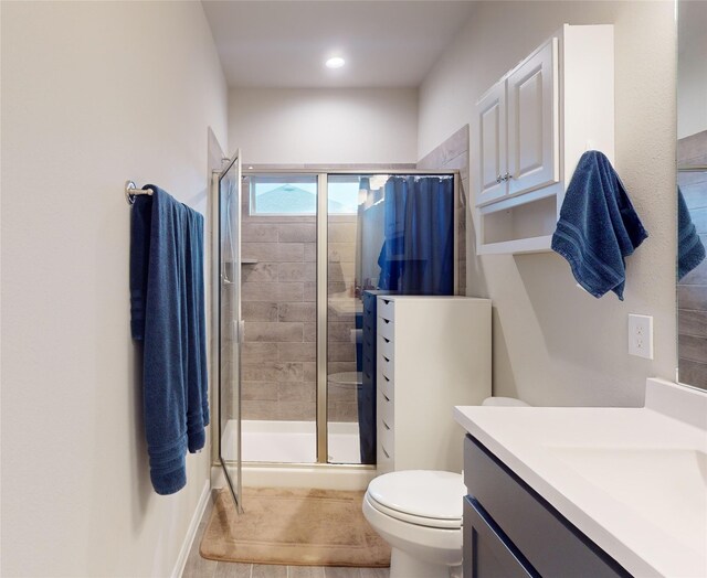 bathroom with vanity, toilet, and a shower with shower door