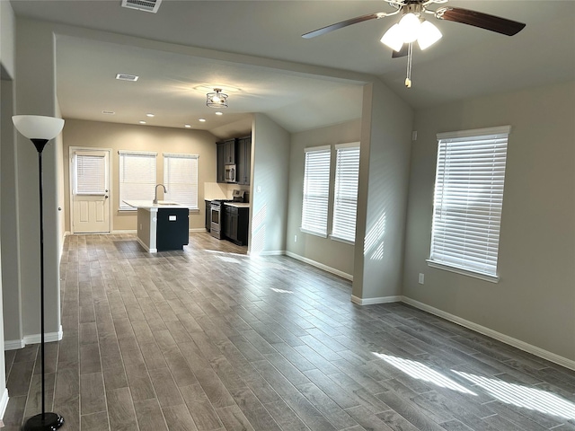 unfurnished living room featuring sink, ceiling fan, and a wealth of natural light