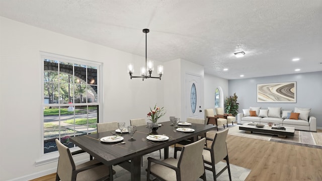 dining area with wood-type flooring, a textured ceiling, and a chandelier