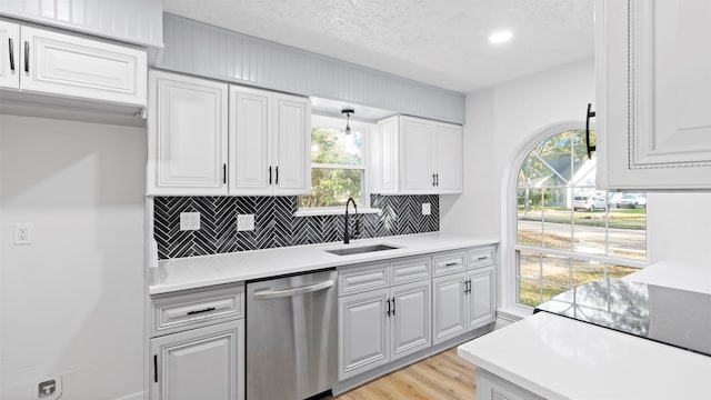 kitchen featuring dishwasher, sink, light hardwood / wood-style floors, decorative light fixtures, and decorative backsplash