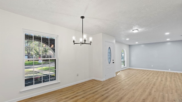 interior space featuring a chandelier, a textured ceiling, and light wood-type flooring