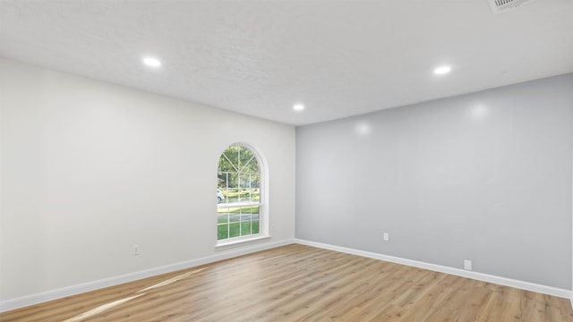 empty room with light hardwood / wood-style floors and a textured ceiling