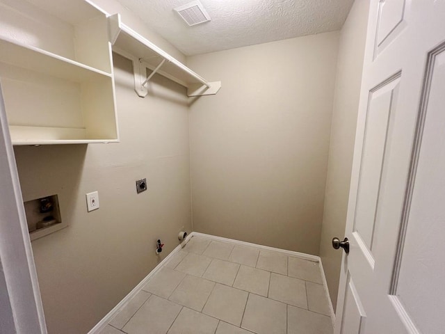 clothes washing area featuring electric dryer hookup, hookup for a gas dryer, washer hookup, light tile patterned floors, and a textured ceiling