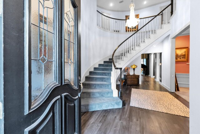 foyer entrance featuring dark hardwood / wood-style flooring, a towering ceiling, and an inviting chandelier