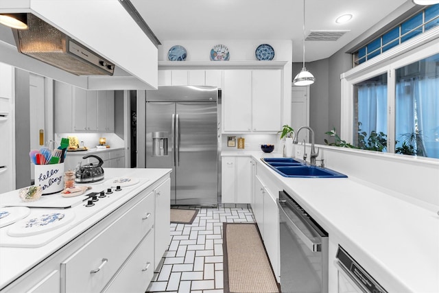 kitchen featuring white cabinetry, sink, extractor fan, decorative light fixtures, and appliances with stainless steel finishes