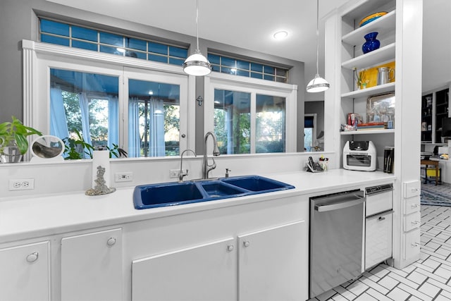 kitchen featuring pendant lighting, sink, stainless steel dishwasher, a wealth of natural light, and white cabinetry