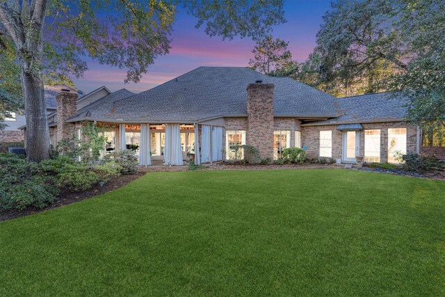 back house at dusk with a lawn