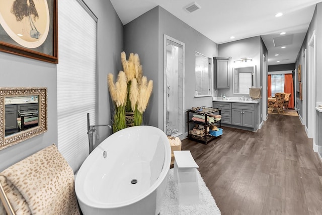 bathroom featuring hardwood / wood-style flooring, vanity, and separate shower and tub