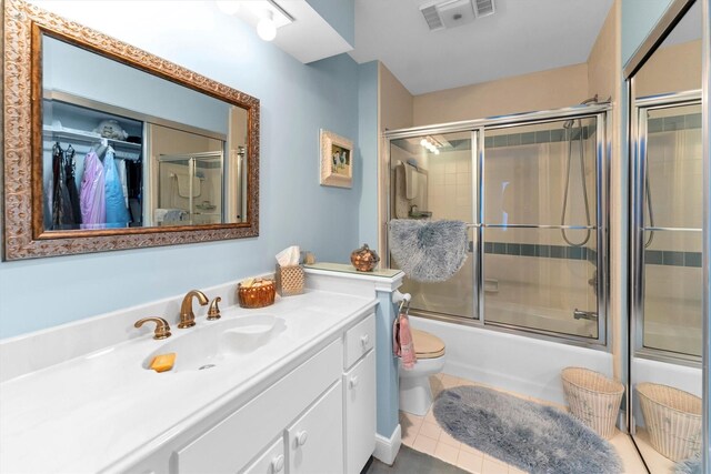 full bathroom featuring tile patterned flooring, vanity, enclosed tub / shower combo, and toilet