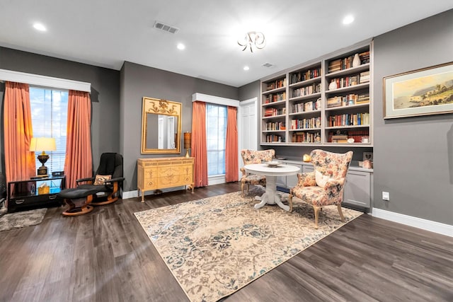 sitting room with a healthy amount of sunlight, dark hardwood / wood-style flooring, and built in shelves