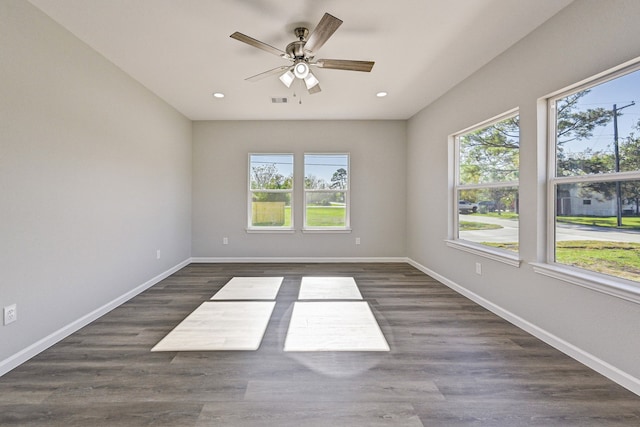 empty room featuring a wealth of natural light, dark wood-type flooring, and ceiling fan