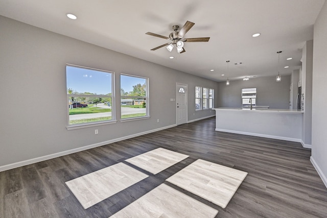 unfurnished living room featuring ceiling fan and dark wood-type flooring