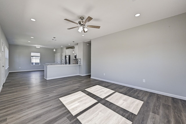 unfurnished living room featuring ceiling fan and dark wood-type flooring