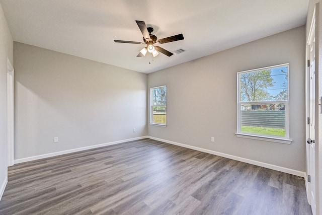 empty room with ceiling fan, plenty of natural light, and hardwood / wood-style floors