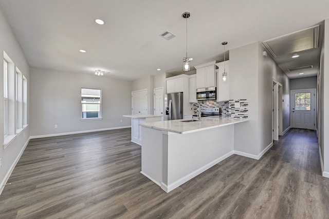 kitchen featuring white cabinets, decorative light fixtures, stainless steel appliances, and a healthy amount of sunlight