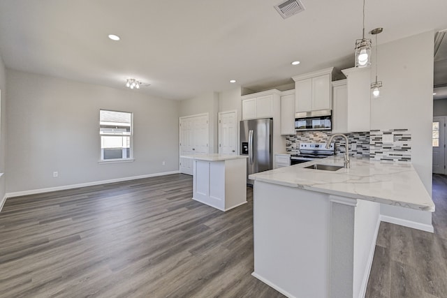 kitchen featuring dark wood-type flooring, stainless steel appliances, a kitchen island, decorative light fixtures, and white cabinets