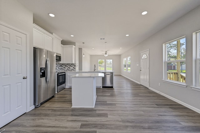 kitchen with hardwood / wood-style floors, white cabinets, decorative light fixtures, kitchen peninsula, and stainless steel appliances