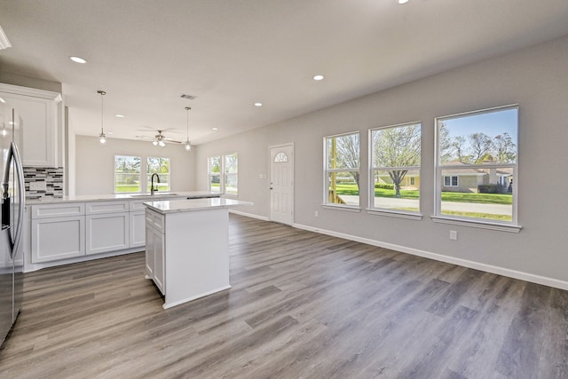 kitchen featuring white cabinets, sink, hanging light fixtures, a kitchen island, and wood-type flooring