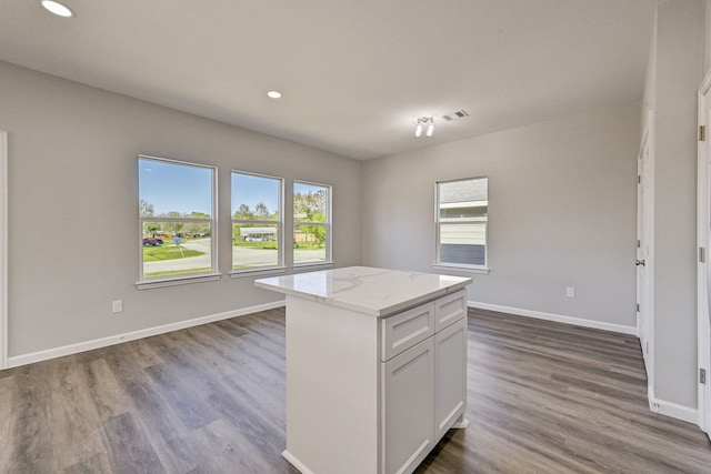 kitchen featuring hardwood / wood-style flooring, plenty of natural light, a kitchen island, and white cabinetry