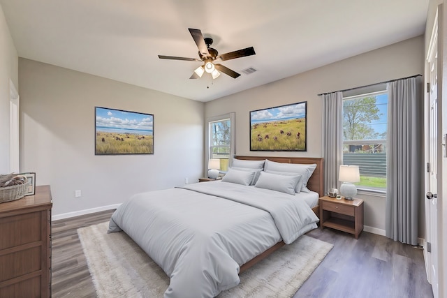 bedroom with ceiling fan, dark wood-type flooring, and multiple windows