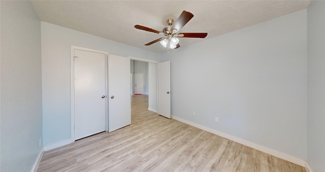 unfurnished bedroom with a textured ceiling, light wood-type flooring, and ceiling fan