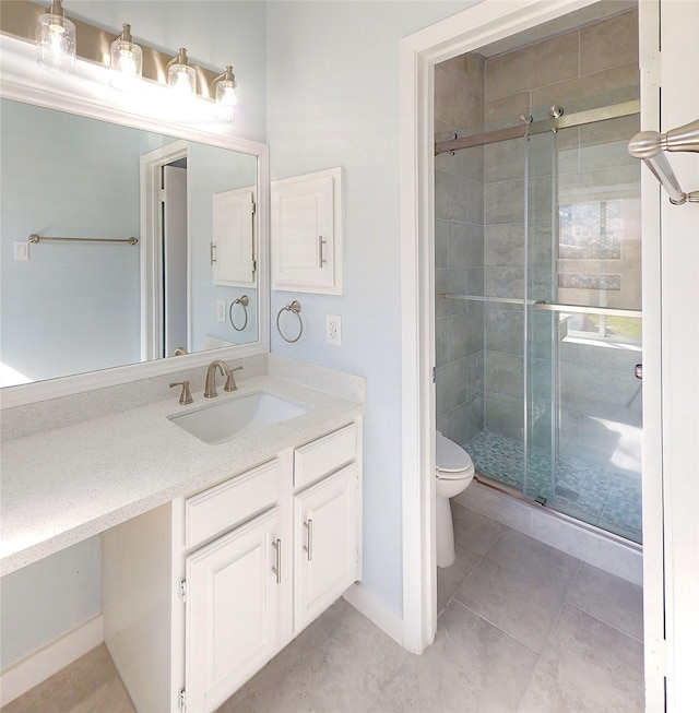 bathroom featuring tile patterned floors, vanity, toilet, and a shower with shower door