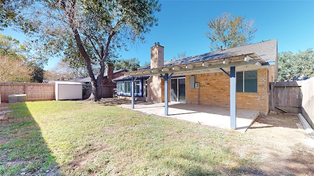 back of property featuring a shed, a yard, and a patio