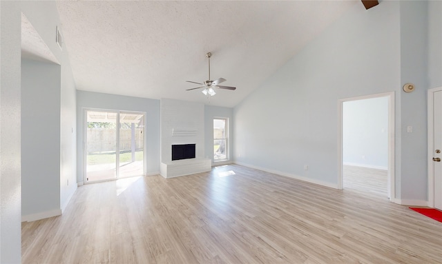 unfurnished living room with a fireplace, a textured ceiling, light wood-type flooring, and high vaulted ceiling