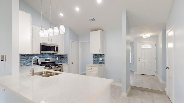 kitchen with white cabinetry, sink, stainless steel appliances, tasteful backsplash, and kitchen peninsula