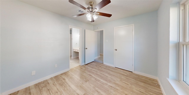 unfurnished bedroom featuring a closet, light wood-type flooring, ensuite bathroom, and ceiling fan