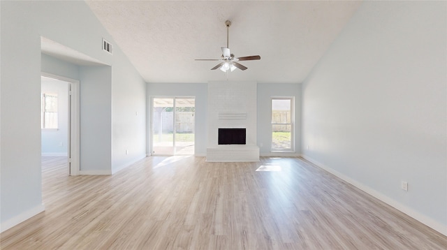 unfurnished living room featuring a fireplace, light hardwood / wood-style flooring, a healthy amount of sunlight, and vaulted ceiling