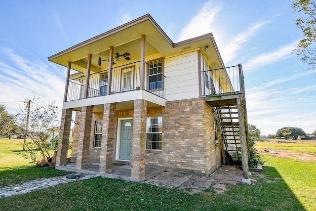 view of front of house with ceiling fan, a balcony, and a front lawn