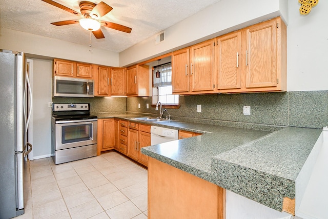 kitchen featuring a textured ceiling, ceiling fan, sink, and stainless steel appliances