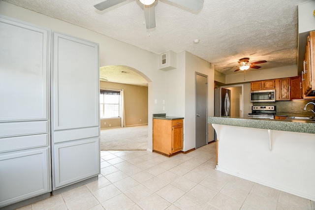 kitchen with sink, light tile patterned floors, a textured ceiling, and appliances with stainless steel finishes