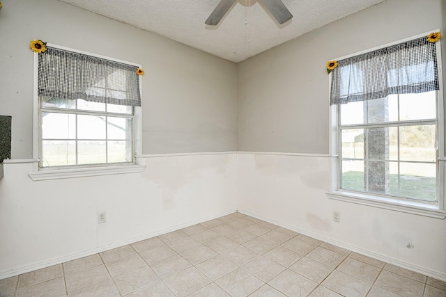 tiled spare room with a textured ceiling and ceiling fan