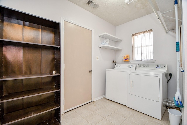 washroom featuring a textured ceiling, separate washer and dryer, and light tile patterned flooring