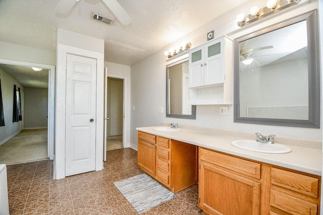 bathroom with ceiling fan, a textured ceiling, and vanity