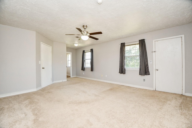 empty room with light carpet, ceiling fan, and a textured ceiling