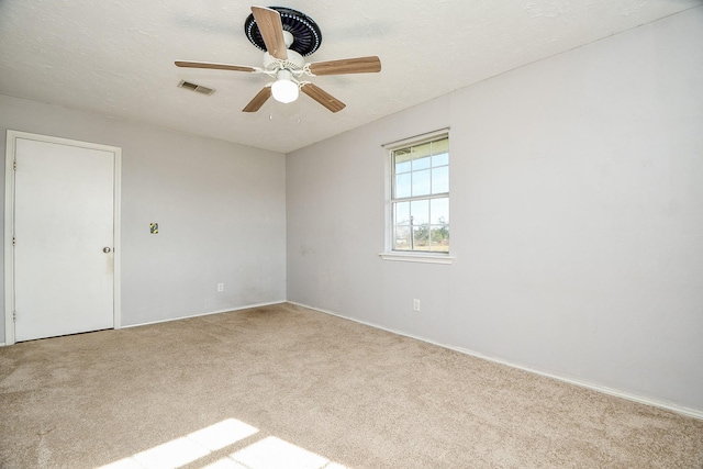 spare room featuring a textured ceiling, ceiling fan, and light carpet