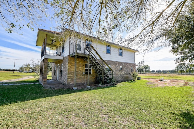 back of house featuring a lawn, ceiling fan, and a balcony