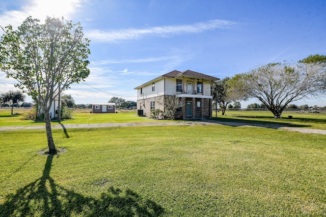 view of front of house with cooling unit, a balcony, and a front lawn