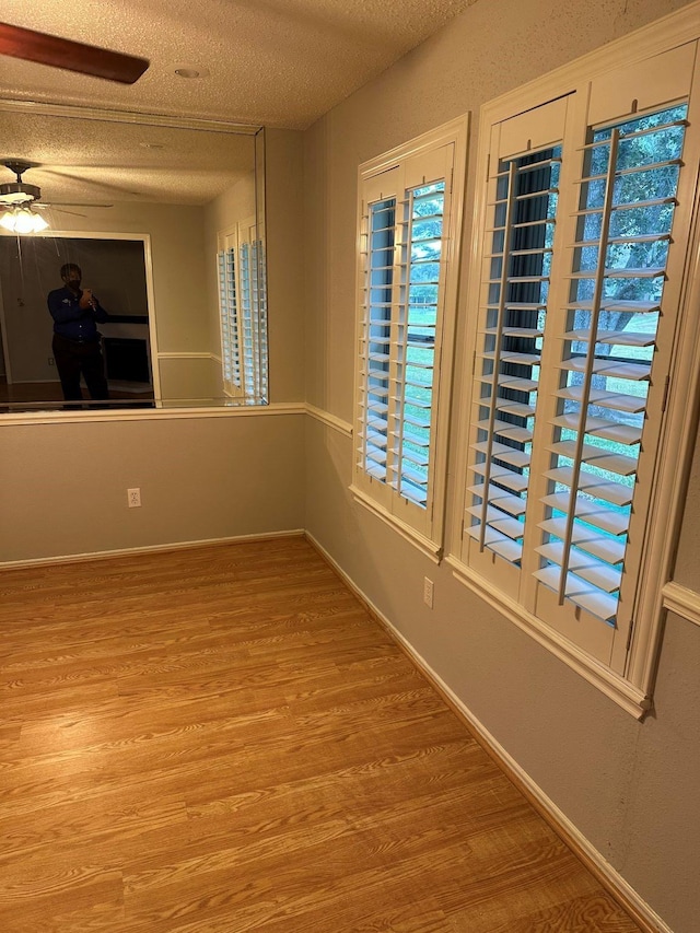 empty room featuring ceiling fan, a textured ceiling, and light wood-type flooring