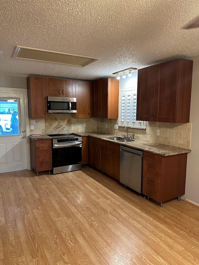 kitchen featuring a textured ceiling, stainless steel appliances, light hardwood / wood-style floors, and sink