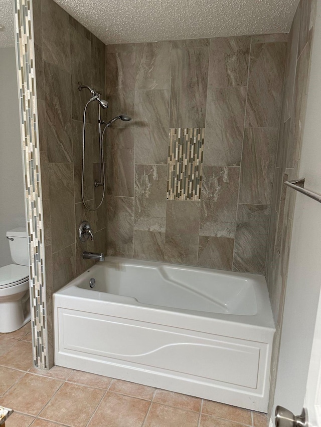 bathroom with a textured ceiling, toilet, tile patterned floors, and tiled shower / bath